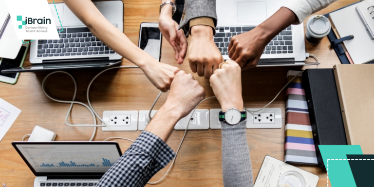 What is Crowdsourcing? A Comprehensive Guide | People working around a desk with computers and other electronic devices.